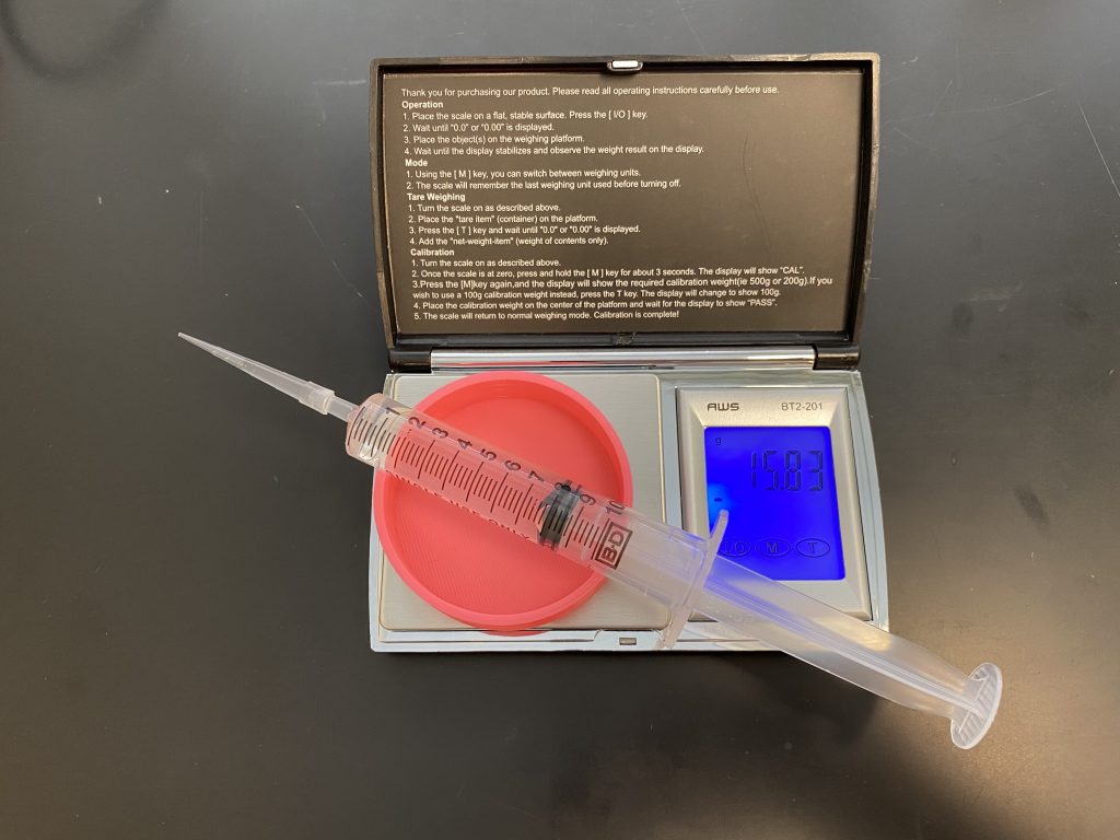 A syringe with clear liquid on a digital scale